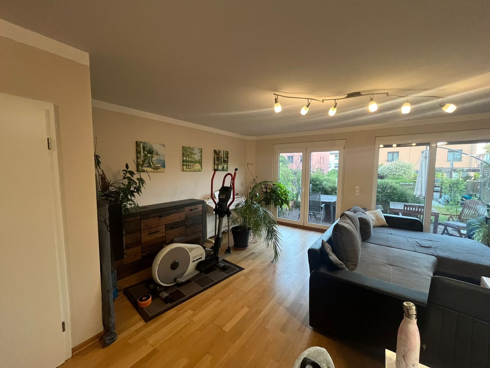 Vorher: Wohnbereich mit Crosstrainer, Sideboard und Sofa